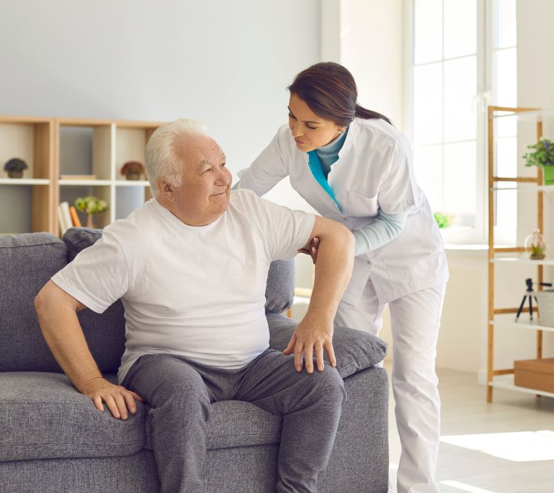 Caregiver helping a senior with Parkinson's move
