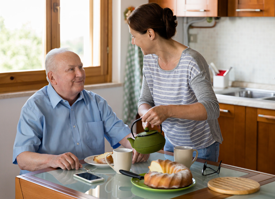 women helping elderly man in kitchen
