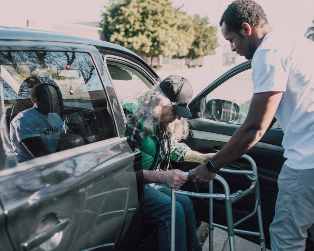 caregiver helping man out of car in San Diego
