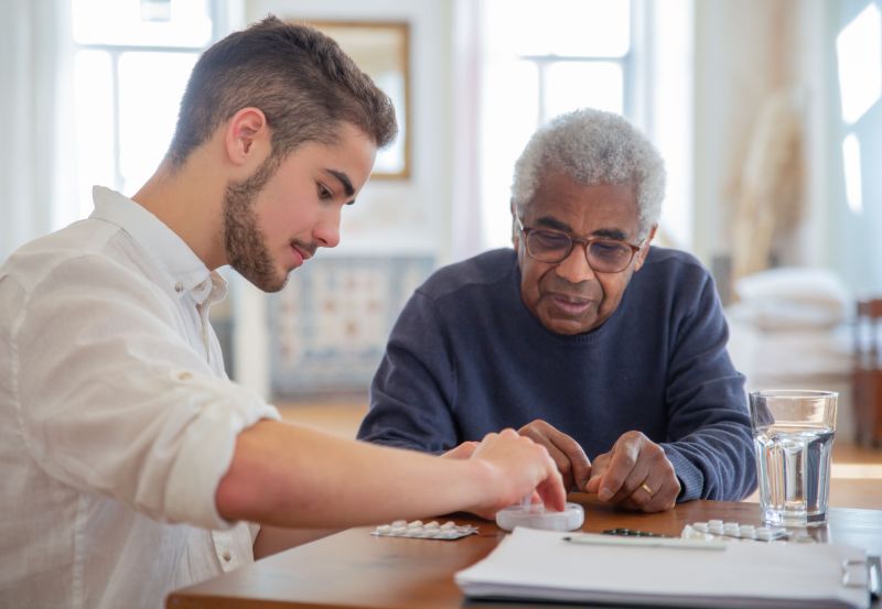 young man helping older man with his medications