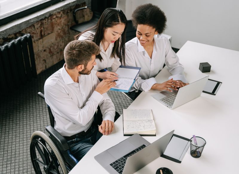 A worker in a wheelchair working with other co-workers in office.
