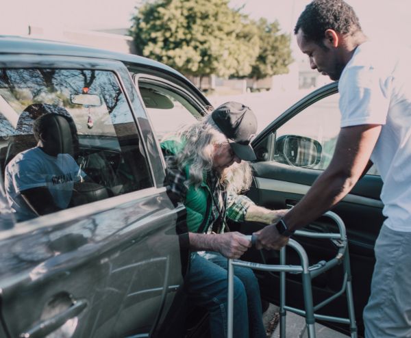caregiver helping man from car