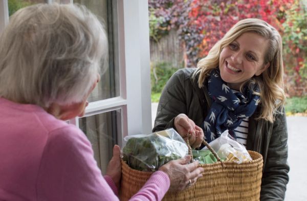 woman delivering food to senior