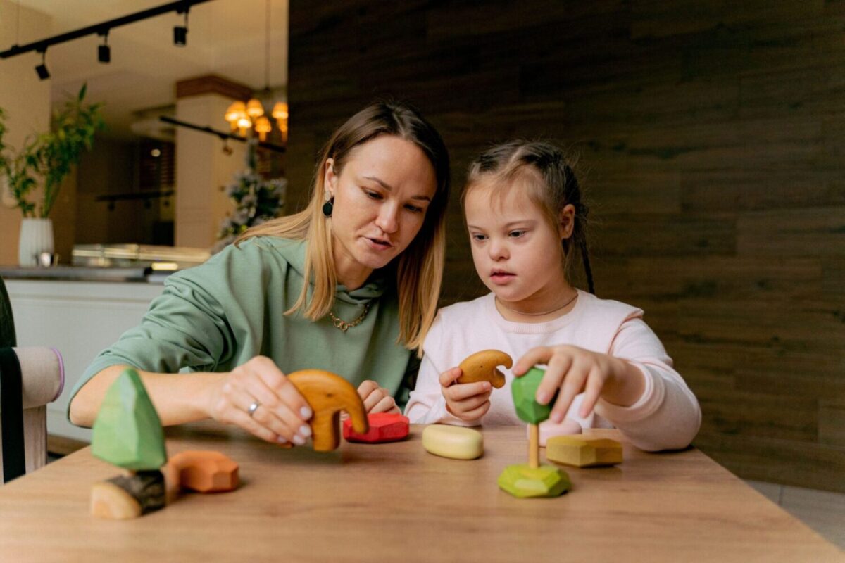 Caregiver supporting a child with special needs during an activity.