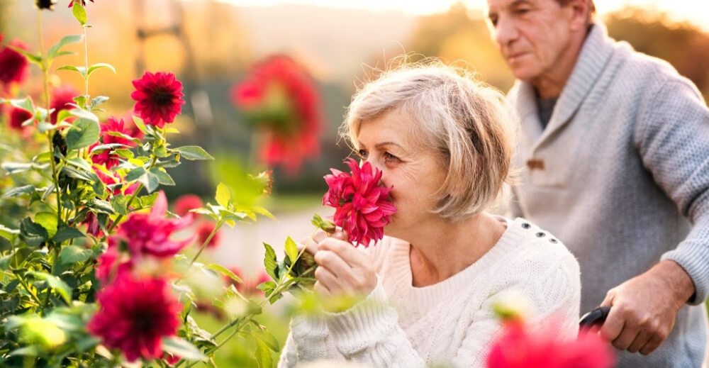 Older woman smelling flowers outside