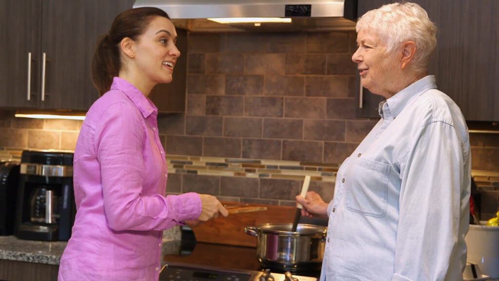 Woman helping elderly make dinner