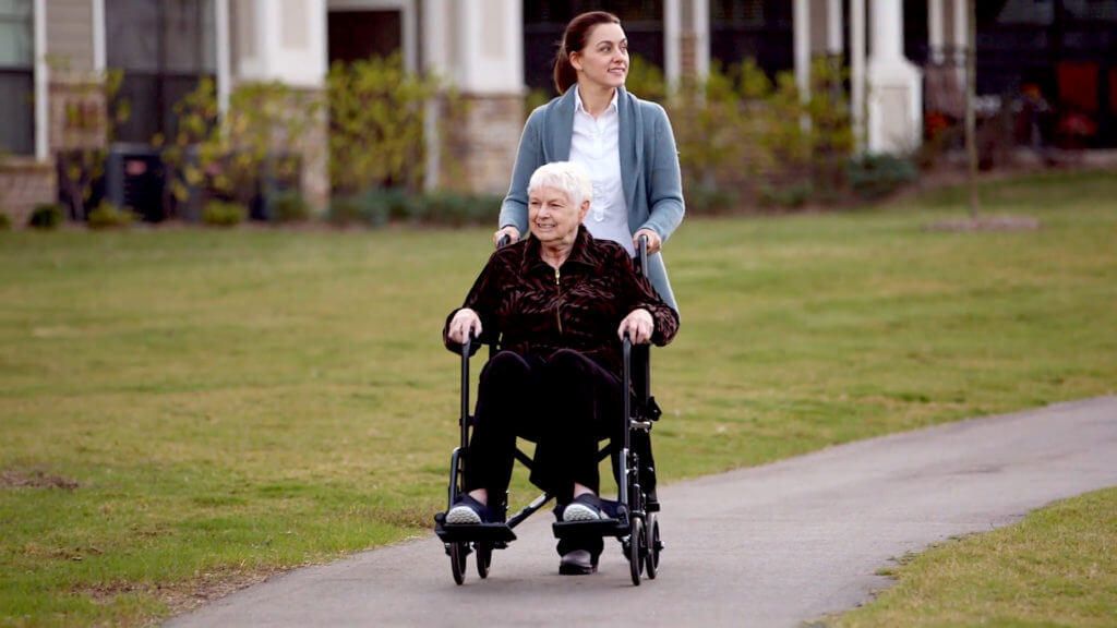 Young nurse pushing older woman in wheelchair