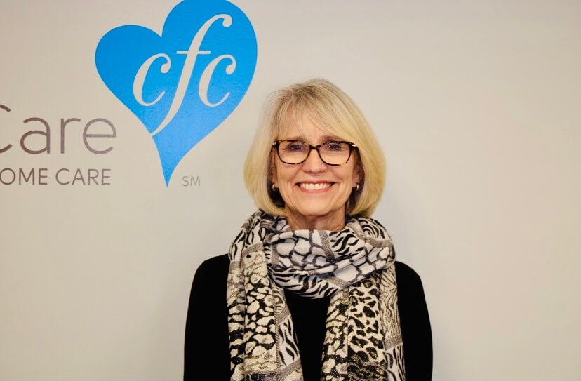 An in-home care nurse smiling next to the logo.