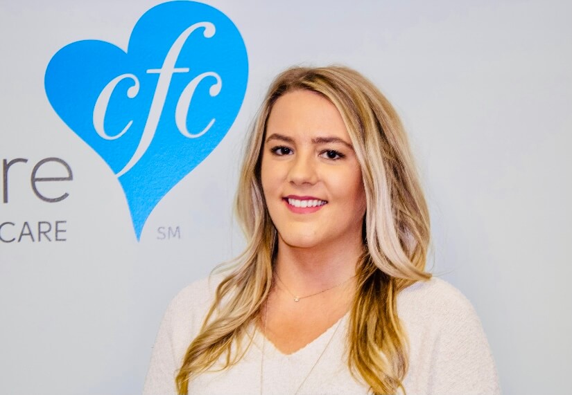 An in-home care nurse smiling next to the logo.