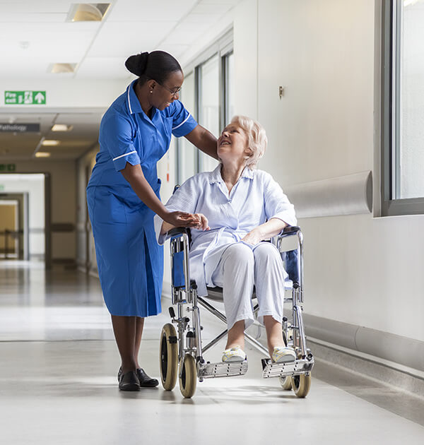 Younger nurse walking with older woman