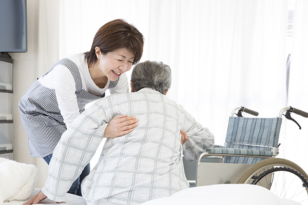 Young nurse helping older woman stand