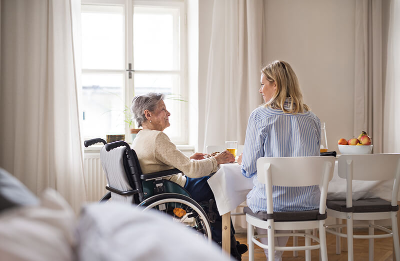 Older patient sitting with young nurse