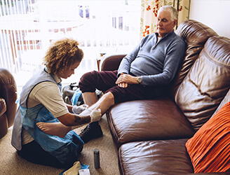 Young nurse helping older man dress