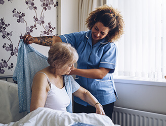 Home nurse helping older woman dress