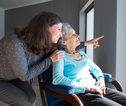 Dementia caregiver with elderly woman looking outside