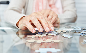 Elderly hands putting together a puzzle.