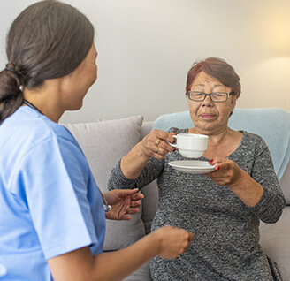 An in-home care nurse and her patient enjoying a cup of tea.