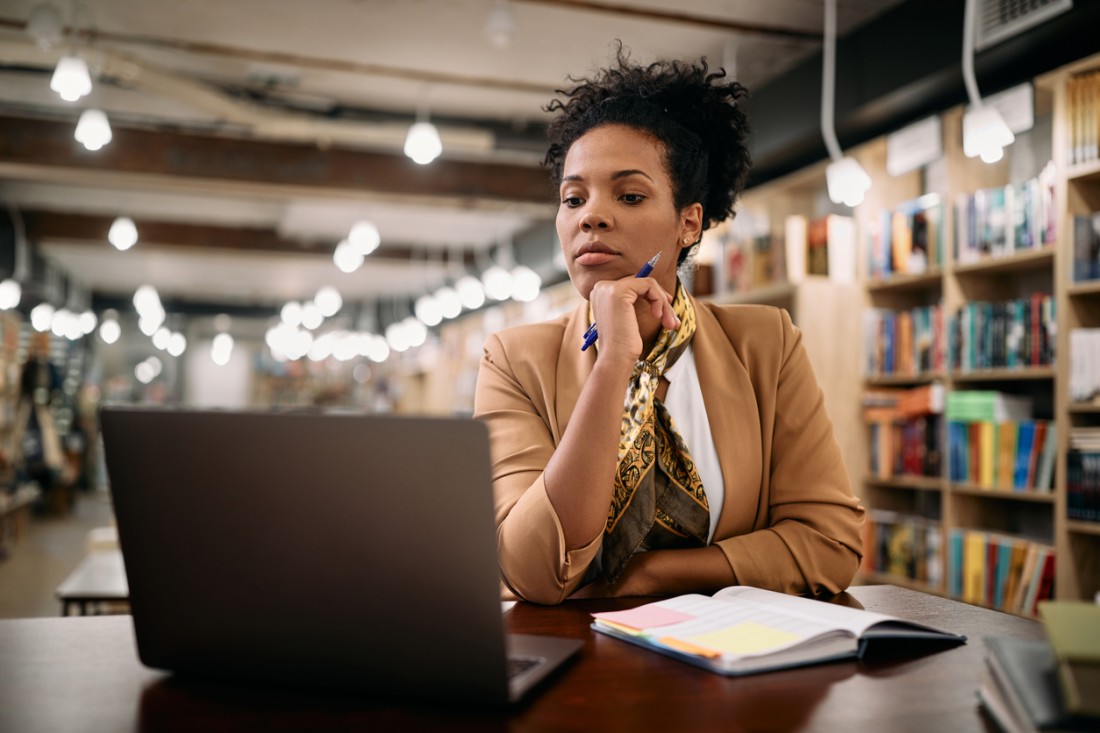 An aspiring entrepreneur does research on her laptop in a library