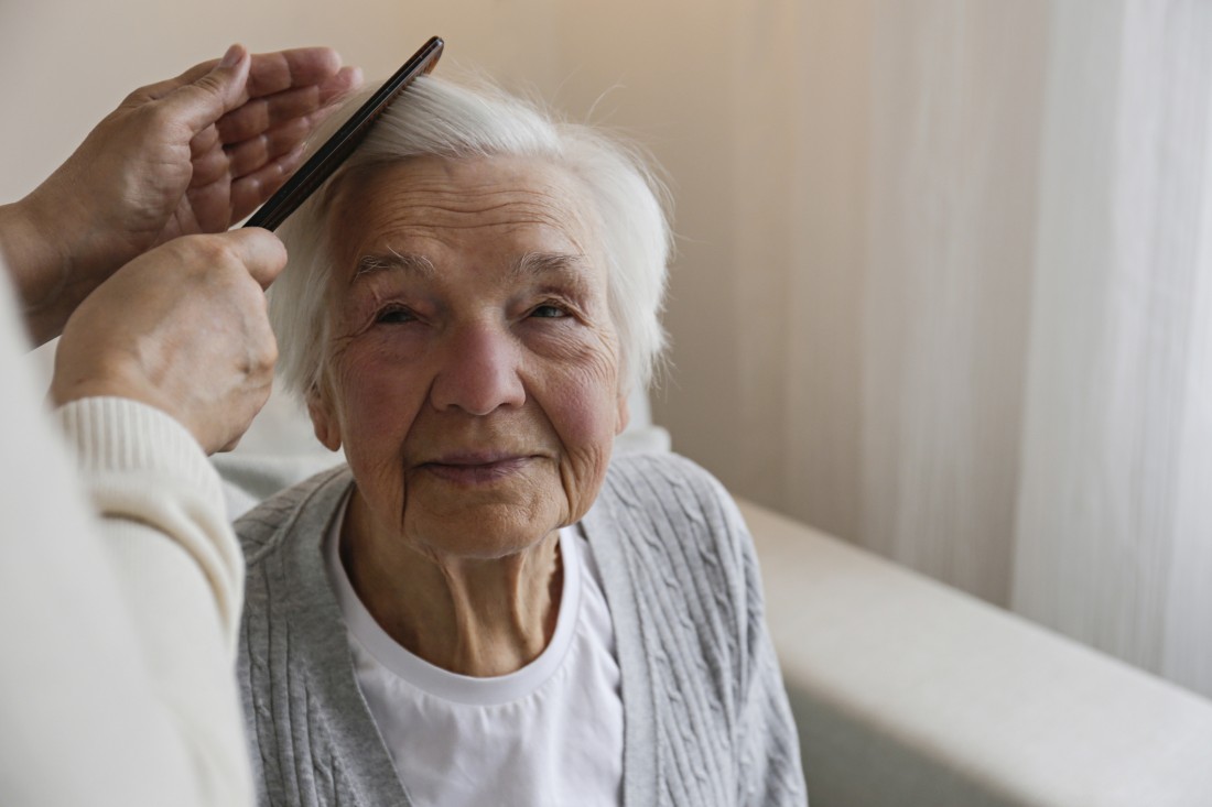 A caregiver combs an older person’s hair