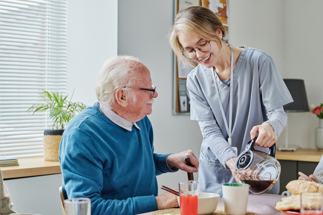 Senior caregiver pouring coffee for a client at his home