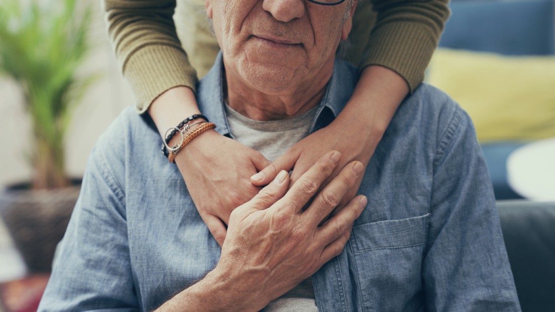 Closeup of a caregiver’s arms around an older man