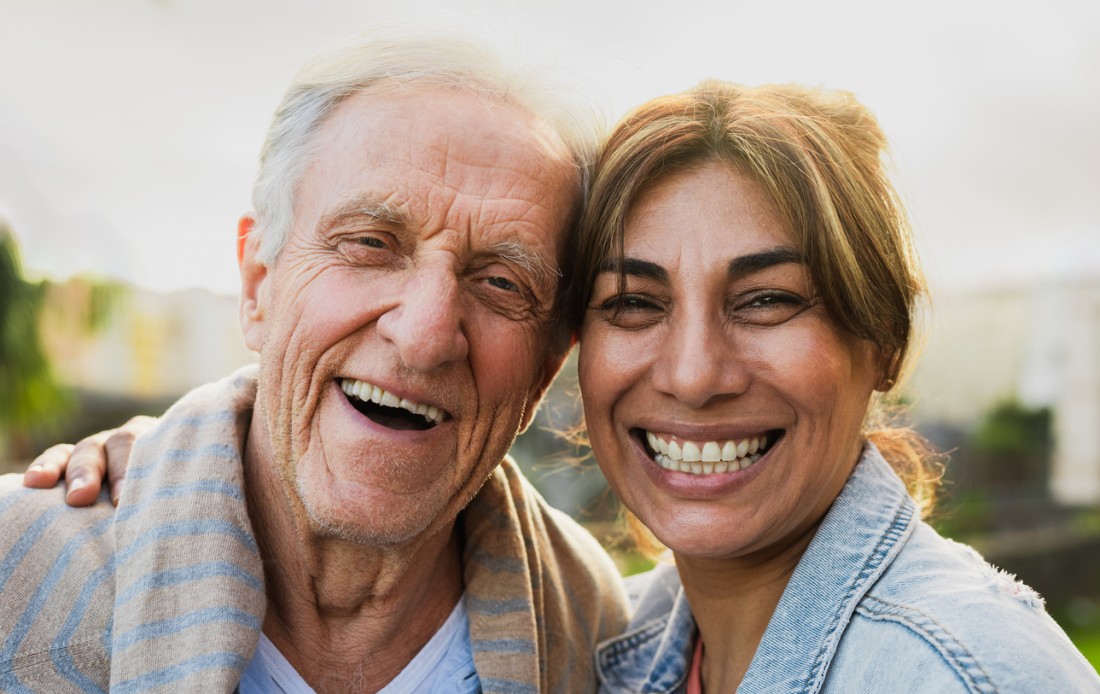 An older man and a caregiver smiling at the camera