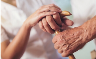 Young nurse clasping hands of older woman