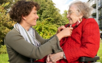 Caregiver assisting senior woman dress for the cold