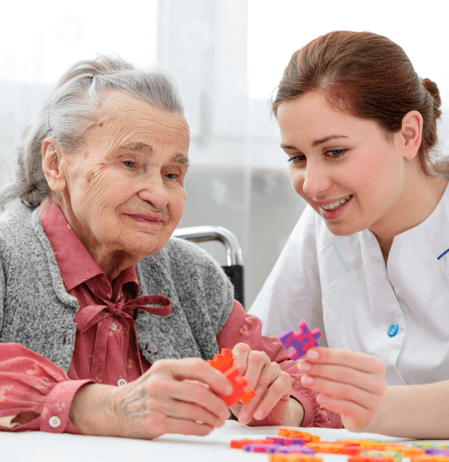 Young nurse helping older woman with a puzzle