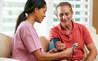 Home nurse checking older man's blood pressure