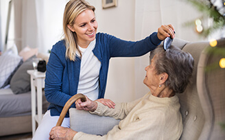 Young nurse brushing older patient's hair