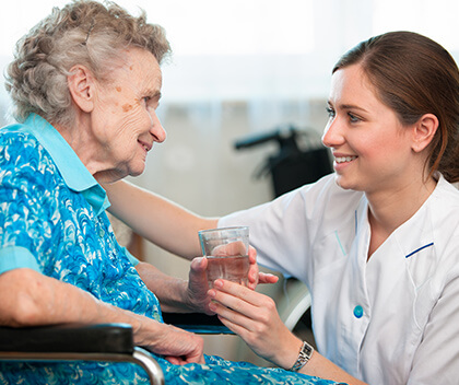 Home nurse giving older woman water