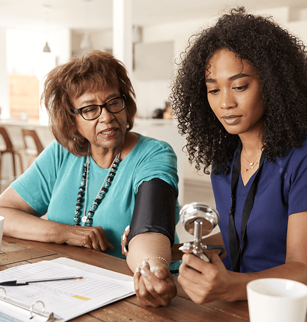 Home nurse giving older woman a blood pressure test