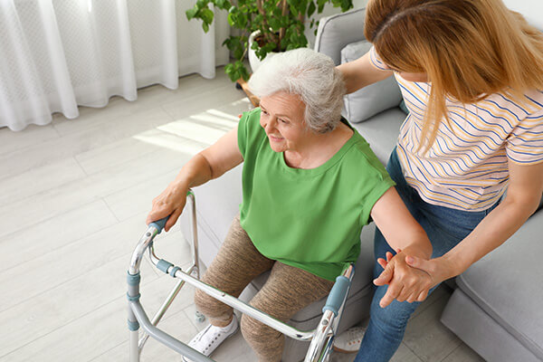 Dementia caregiver providing mobility support to elderly woman