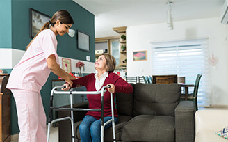 Home nurse helping an elderly woman stand up