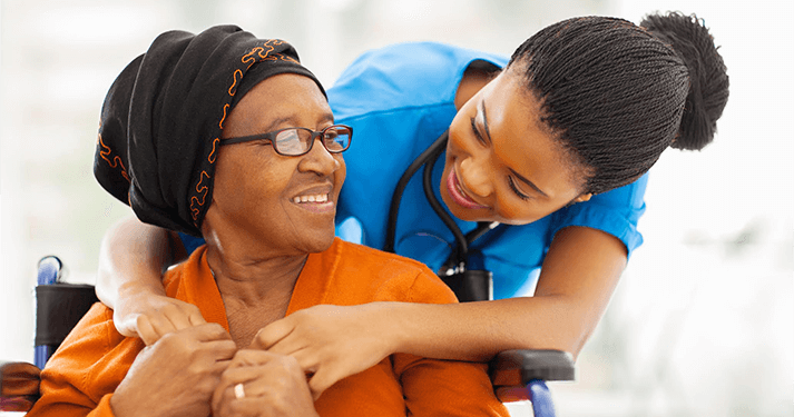 Young caregiver putting shoe on elderly woman