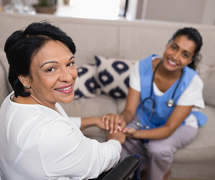 Home nurse and older woman holding hands and smiling 