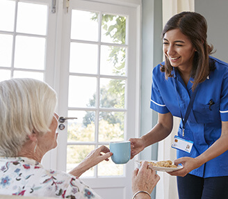 A nurse hands her patient a cup of tea.