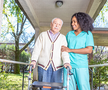 Young nurse helping older man walk with walker