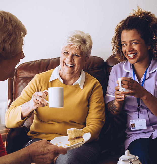 Older woman laughing with younger home nurses