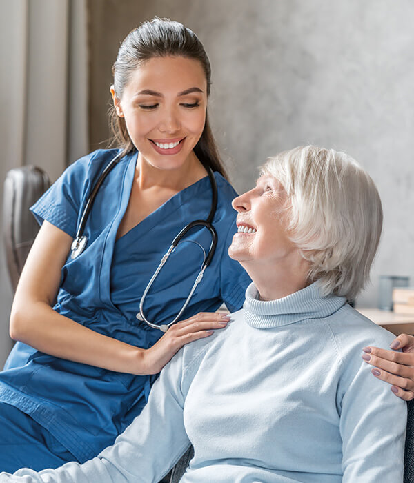 Young nurse sitting with older patient