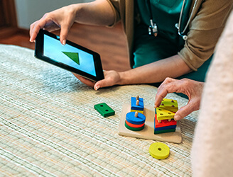 Older man working with blocks with nurse holding tablet