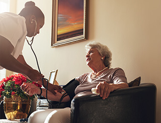 Young nurse checking blood pressure of older woman