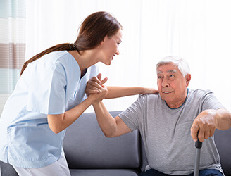 Younger nurse helping older man stand up