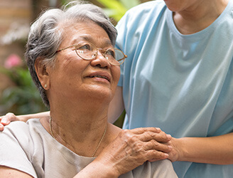 Older woman holding home nurse's hand on her shoulder