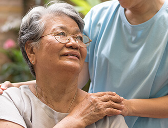 Young nurse with hand on shoulder of older woman