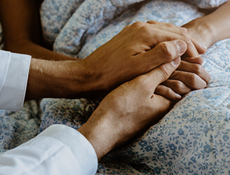 Home nursing holding older patient's hand