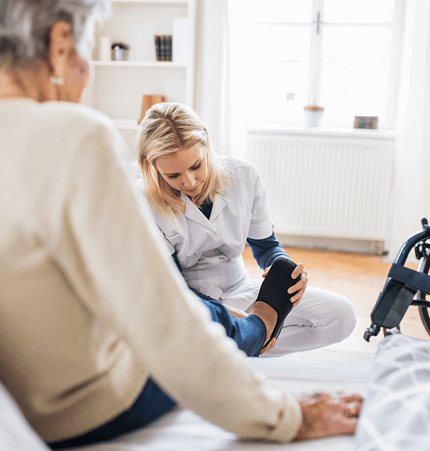 Young nurse putting shoe on older woman