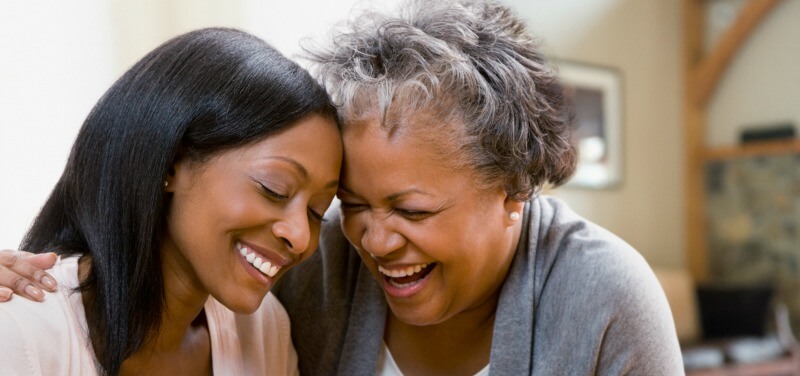 Young nurse embracing and laughing with older woman