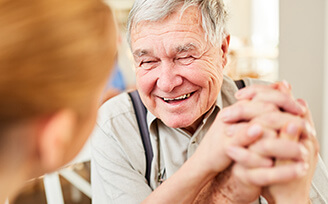 Older man clasping hands with young nurse
